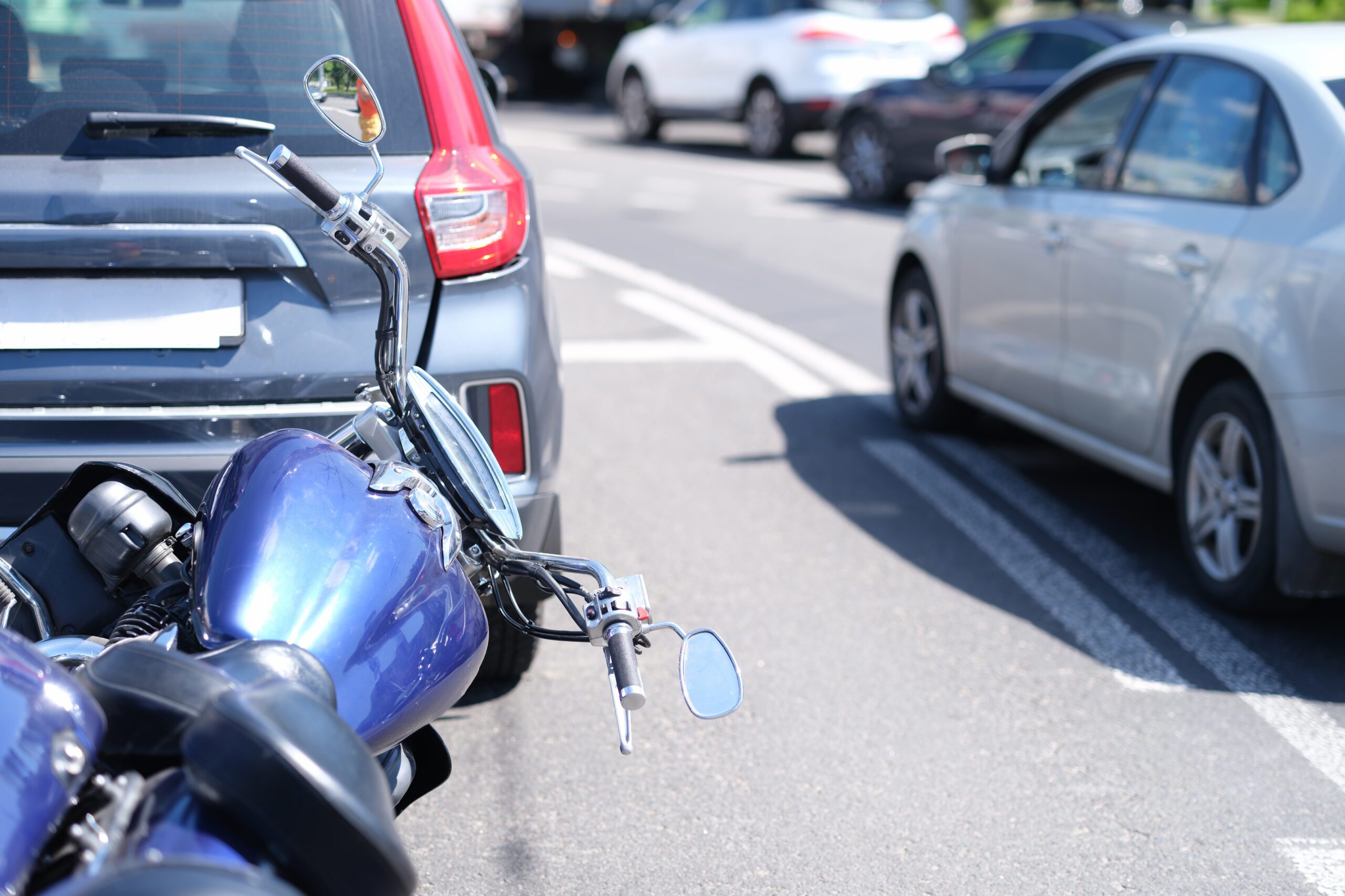 Blue motorcycle lying in front of car on road closeup. Car and motorcycle insurance concept